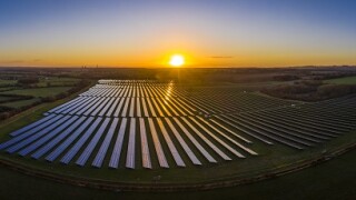 Aerial looking over a modern solar farm at sunrise in the English countryside panoramic