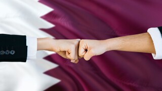 Qatar agreement concept. Man and woman fist bumping on national flag to show cooperation. Peace and teamwork theme.
