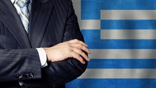 Politician crossed arms of on Greek flag background