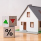 Wooden blocks percentage sign, arrow up and down with house model background. Central bank FED control interest rate increase or decrease effect to house price, monthly payment, buying home concept.