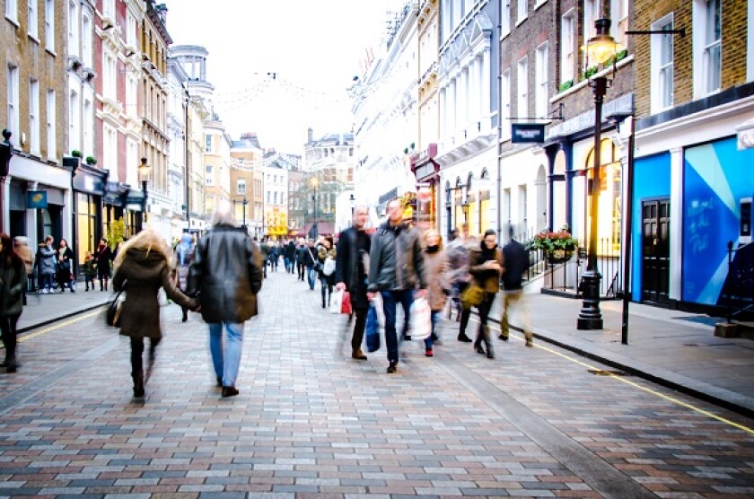 Motion blurred people on busy city street of shops