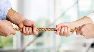 Tug war, two businessman pulling a rope in opposite directions isolated on white background