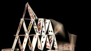 House of cards collapsing on dark backgroun
