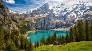 Amazing tourquise Oeschinnensee with waterfalls, wooden chalet a