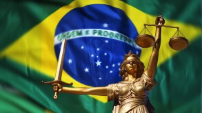 Lady Justice statue against a background of the Brazilian flag