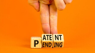 Patent pending symbol. Concept words Patent pending on wooden cubes. Businessman hand. Beautiful orange table orange background. Business and patent pending concept. Copy space.