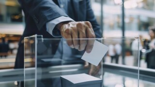 A close up of shareholders hand casting vote in transparent ballot box, showcasing importance of participation in decision making.