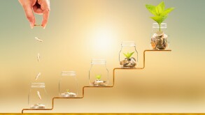 Investor hand hold and drop a gold coin in the five bottle and p