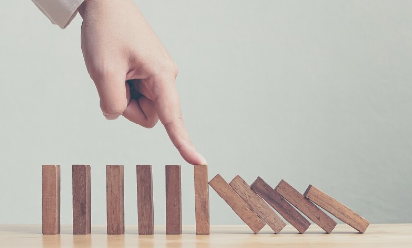 Hand stopping wooden domino business crisis effect or risk protection concept