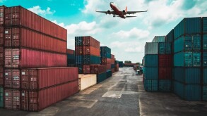 Cargo container for overseas shipping in shipyard with airplane in the sky .