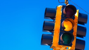 A yellow traffic light with a sky blue background