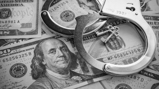 Pair of metal police handcuffs on USD US dollar banknotes money