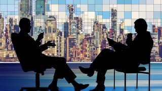Silhouetted seated figures in discussion, with a city skyline in the background