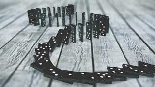 Black dominoes chain on a dark table. Domino effect concept