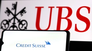 Smartphone with Credit Suisse Bank logo on background of UBS Ban