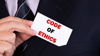 Businessman putting a card with text code of ethics in the pocket