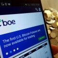 KONSKIE, POLAND - MAY 14, 2018: CBOE Global Markets website displayed on smartphone and stack of coins