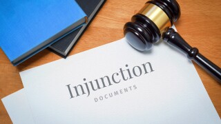 Injunction. Document with label. Desk with books and judges gavel in a lawyer's office.