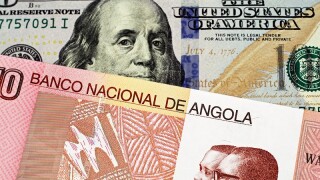 A macro image of a colorful Angolan ten kwanza bill with an American one hundred dollar bill close up