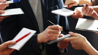 Elegant man signing autograph in notebook on dark background