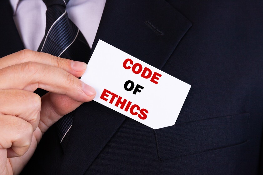 Businessman putting a card with text code of ethics in the pocket
