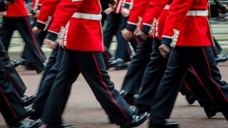 Queen's Royal Guard soldiers walking in red coat uniforms in mot