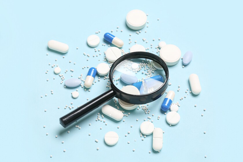 Magnifier with pills on blue background
