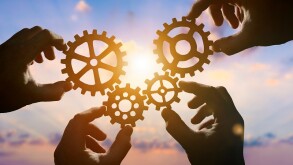 Four hands of businessmen collect gear from the gears of the det