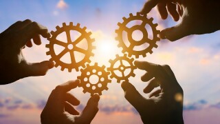 Four hands of businessmen collect gear from the gears of the det