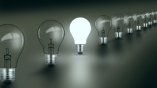 Row of lightbulbs with one illuminated