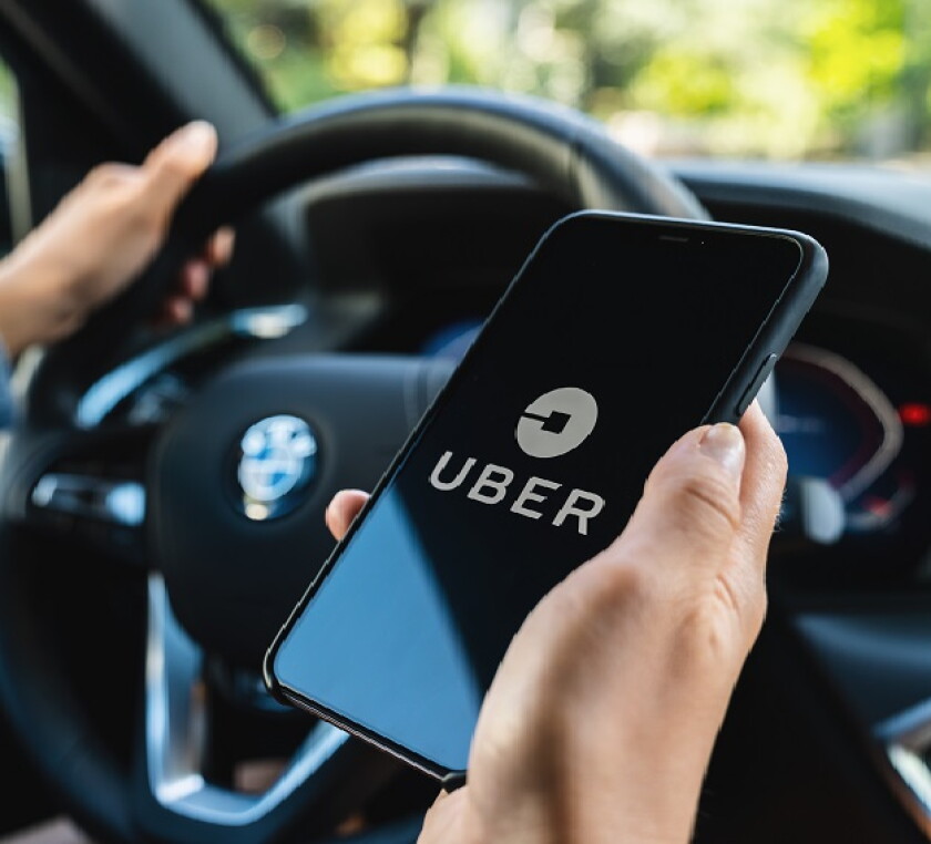BERLIN, GERMANY JULY 2019: Uber driver holding smartphone in car. Uber is an American company offering transportation services online. Illustrative editorial.